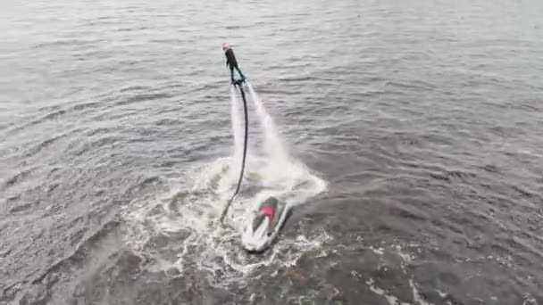 Esportes aquáticos - um homem voando sobre a água com um jet ski nas proximidades - vista aérea — Vídeo de Stock