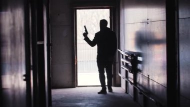 Bir adam elinde silahla odaya girer ve ateş etmeye başlar.