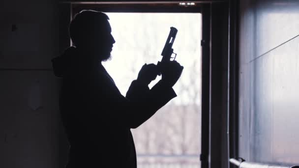 Un hombre tira del obturador de su arma y la tuerce en su mano — Vídeo de stock