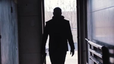 Bir adam karanlık odada yürür ve silahını çıkarır.