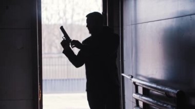 Adamın karanlık silueti silahın kepenğini indirir ve ilerler.