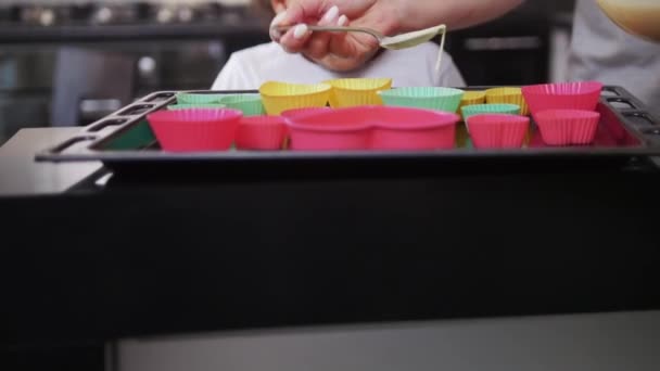 Nero poco sorridente ragazza guardando il suo bianco madre versando pasta in il forme — Video Stock