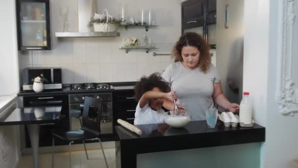 Klein zwart meisje met haar witte moeder het maken van een deeg voor de cupcakes — Stockvideo