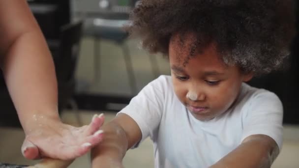 Familienbacken - schwarzes kleines Mädchen und ihre Mutter backen Cupcakes - das Mädchen mit Mehl bedeckt und spielt mit Teig — Stockvideo