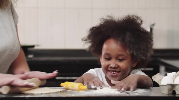 Menina preta com sua mãe na cozinha - a menina brincando com farinha — Vídeo de Stock