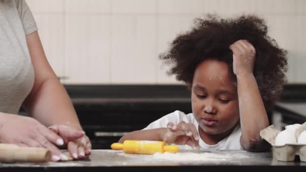 Fekete kislány az anyjával tésztát csinál - a lány hozzáér a liszthez — Stock videók