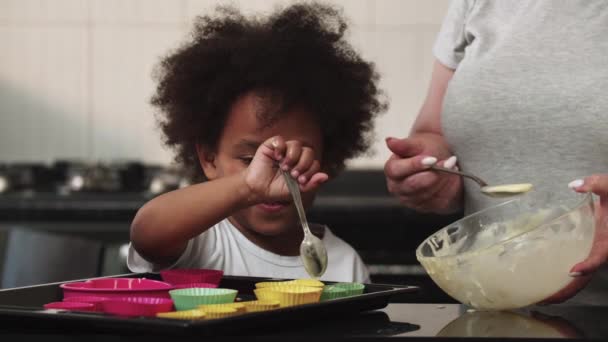 Famille mixte faisant des cupcakes verser de la pâte liquide crue dans les moules à gâteau — Video