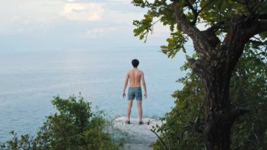 Genç adam kayalıklarda spor yapıyor.