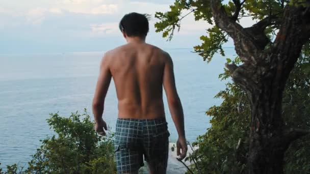 En ung man går till klippan och sträcker ut sin kropp. — Stockvideo
