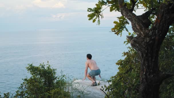 Ung man gör sport övningar på klippan tidigt på morgonen — Stockvideo