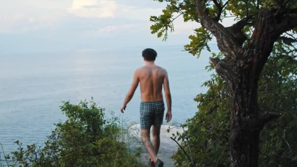 En ung man går till klippan och sträcker sig — Stockvideo