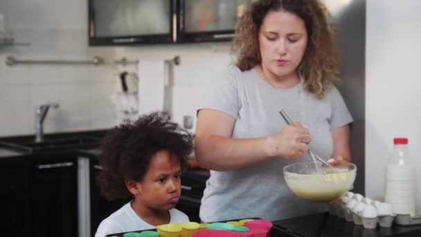 Mère blanche avec sa fille noire mixte faisant de la pâte sur la cuisine — Video