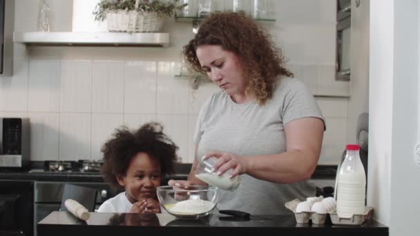 Gemischtes Familienbacken - Mama gießt Milch in eine Glasschüssel für die Teigzubereitung — Stockvideo