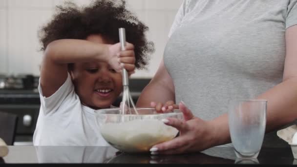 Gemengd familie bakken - zwart klein meisje en haar witte moeder maken deeg in de kom — Stockvideo