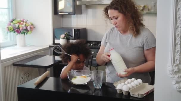 一个黑人小女孩和她的白人妈妈准备为蛋糕做一个面团 — 图库视频影像