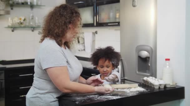 Cuisson familiale - petite fille noire et sa mère blanche travaillant avec de la pâte — Video