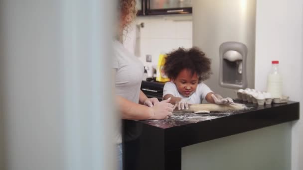 Cuisson familiale - petite fille noire déroulant la pâte avec une corde à sauter et sa mère la regardant — Video