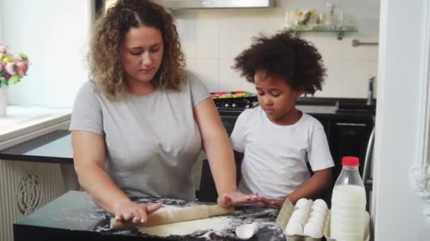 Mélange de cuisson familiale - petite fille noire et sa mère déroulant la pâte avec une corde à sauter — Video