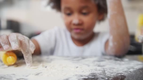 Familie bakken - zwart klein meisje spelen met een bloem op de tafel — Stockvideo