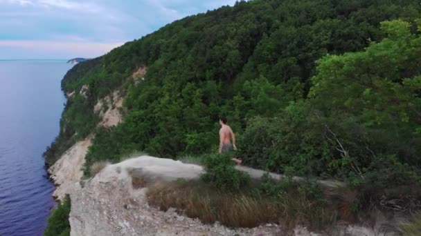 Joven hombre sin camisa hombre libre corriendo a un acantilado y levanta las manos aparte — Vídeos de Stock
