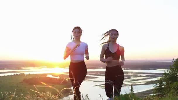 Dvě mladé ženy běhají po hřišti při časném západu slunce — Stock video