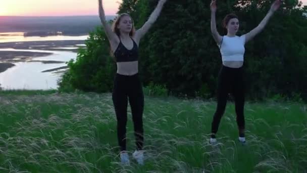 Sahada egzersiz yapan iki genç kadın. Gün batımına kadar. — Stok video
