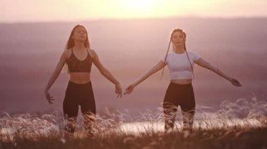 Gün batımında yoga egzersizi yapan iki genç kadın.