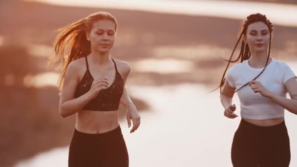 Two young women friends jogging on wheat field while sunset — Stock Video