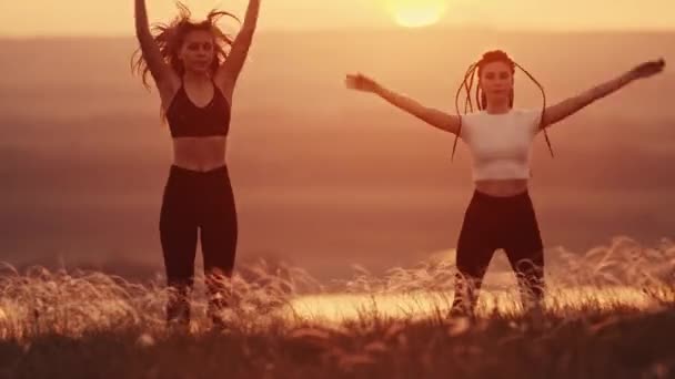 Dvě mladé sportovní ženy dělají rozcvičku na hřišti při západu slunce — Stock video