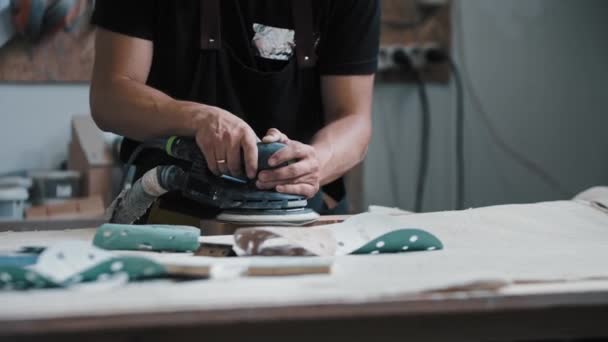Mannen arbetare slipning en träbit i verkstaden med ett instrument — Stockvideo