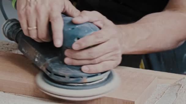 Muž dělník brousí dřevěné kusy pomocí kruhového nástroje — Stock video