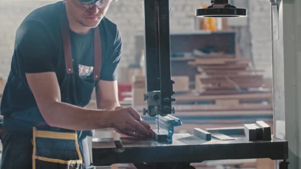 Homme dans un atelier de menuiserie coupant des pièces du détail en bois à l'aide d'une machine de découpe statique — Video