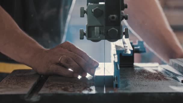 Marangozluk atölyesindeki bir adam kesim makinesi kullanarak ahşap bir detayı iki eşit parçaya bölüyor. — Stok video