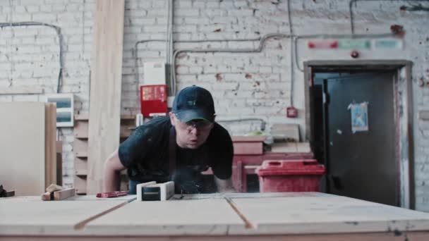Hombre en gafas protectoras en taller de carpintería cortando un pequeño detalle de madera en piezas usando una máquina de corte estática — Vídeos de Stock