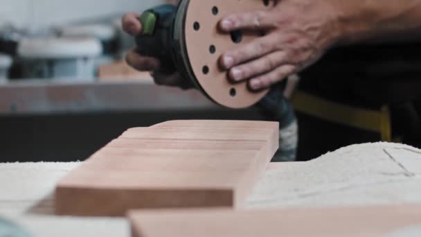 Pracovník držící brusku a začne brousit úhel dřevěných detailů — Stock video