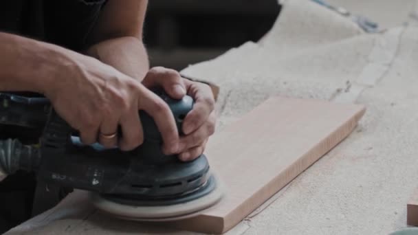 O trabalhador do homem faz a superfície superior de um detalhe de madeira retangular mais macia com uma máquina de moedura — Vídeo de Stock