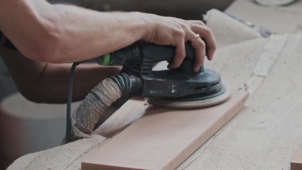Trabalhos de carpintaria - trabalhador faz a superfície superior de um detalhe de madeira retangular mais suave com uma máquina de moagem — Vídeo de Stock