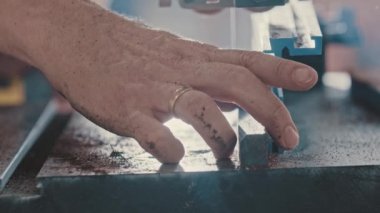 Marangozluk işi. İşçi, küçük bir otomatik testereyle küçük ahşap parçaları kesiyor.