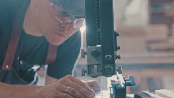 Trabalhos de carpintaria - trabalhador homem cortando lentamente ao longo do detalhe de madeira com uma serra automática tornando-se duas peças — Vídeo de Stock