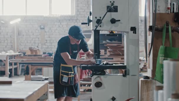 Timmerwerk - arbeider snijden langs het houten detail met een automatische zaag in de werkplaats — Stockvideo