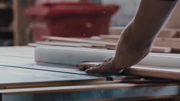 Travaux de menuiserie - l'ouvrier coupe lentement le long détail en bois à l'aide d'une scie automatique — Video