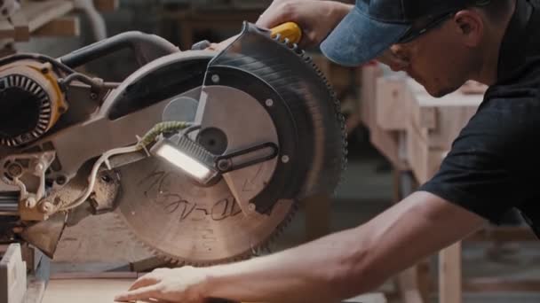Man i en snickeri verkstad skära en liten bit av trä detalj med hjälp av en cirkelsåg — Stockvideo