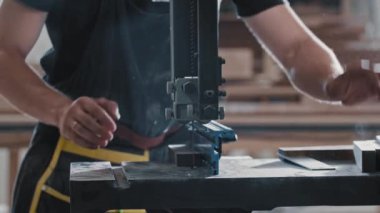 Marangozluk atölyesindeki bir adam kesim makinesi kullanarak küçük tahta parçaları kesiyor.