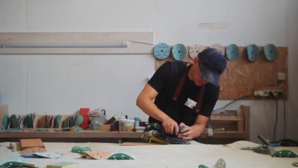 Pekerjaan tukang kayu - pekerja laki-laki dengan kacamata pelindung menggiling permukaan dari detail kayu persegi panjang — Stok Video
