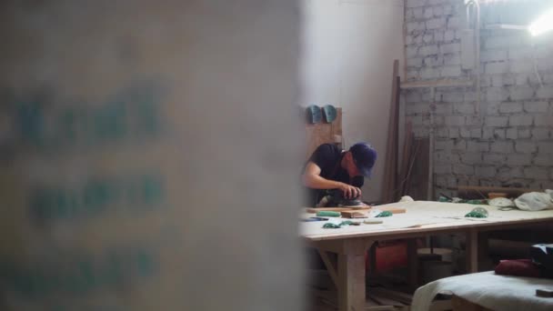 Tischlerarbeiten - Arbeiter in Schutzbrille schleift in Werkstatt die Oberfläche eines Holzdetails — Stockvideo