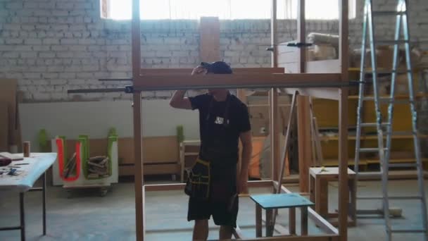 Trabajos de carpintería en el taller - trabajador de pie en la construcción de madera sin terminar — Vídeos de Stock