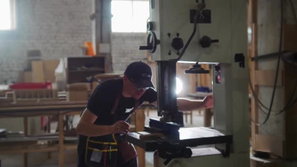 Oficina de carpintaria - o funcionário prepara a serra automática para cortar uma tábua de madeira — Vídeo de Stock
