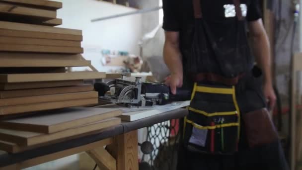 Taller de carpintería: un trabajador camina por el estudio y toma la amoladora — Vídeos de Stock