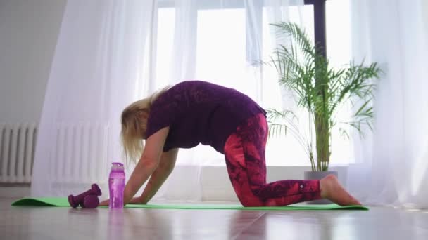 Jóga uvnitř - blondýny nadváha žena dělá cvičení pro ni záda na podložce jógy — Stock video