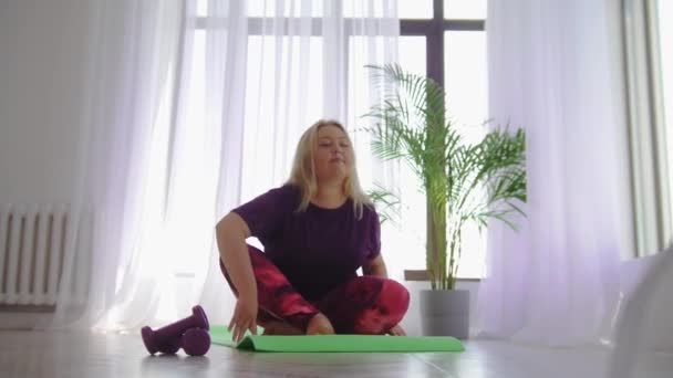 Фітнес-тренування - блондинка надмірна вага жінка нахиляється вперед на йога килимок — стокове відео
